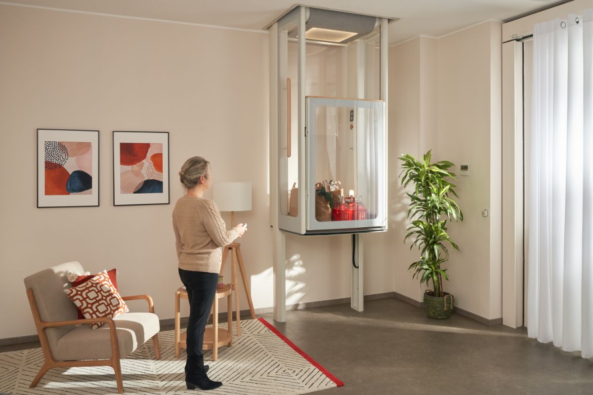 Žena v obývacím pokoji ovládá výtah Uplifts S2, ve kterém má uložený nákup.