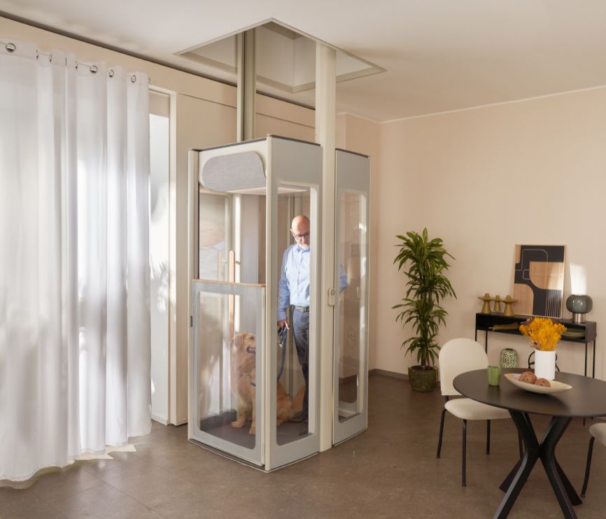 Muž středního věku se psem ve výtahu Uplifts S3 nainstalovaném v moderním obývacím pokoji.
