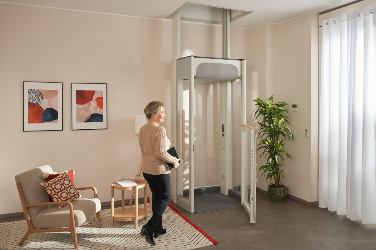Usmívající se žena středního věku jde k domácímu výtahu Uplifts S2.